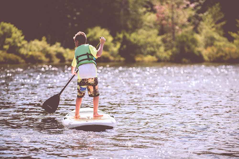 Dečak vozi dasku za veslanje na reci